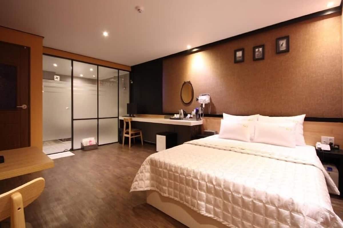 Ein Hotelzimmer mit Bett, Schreibtisch, Stuhl und einer Schiebetür zu einem Badezimmer.