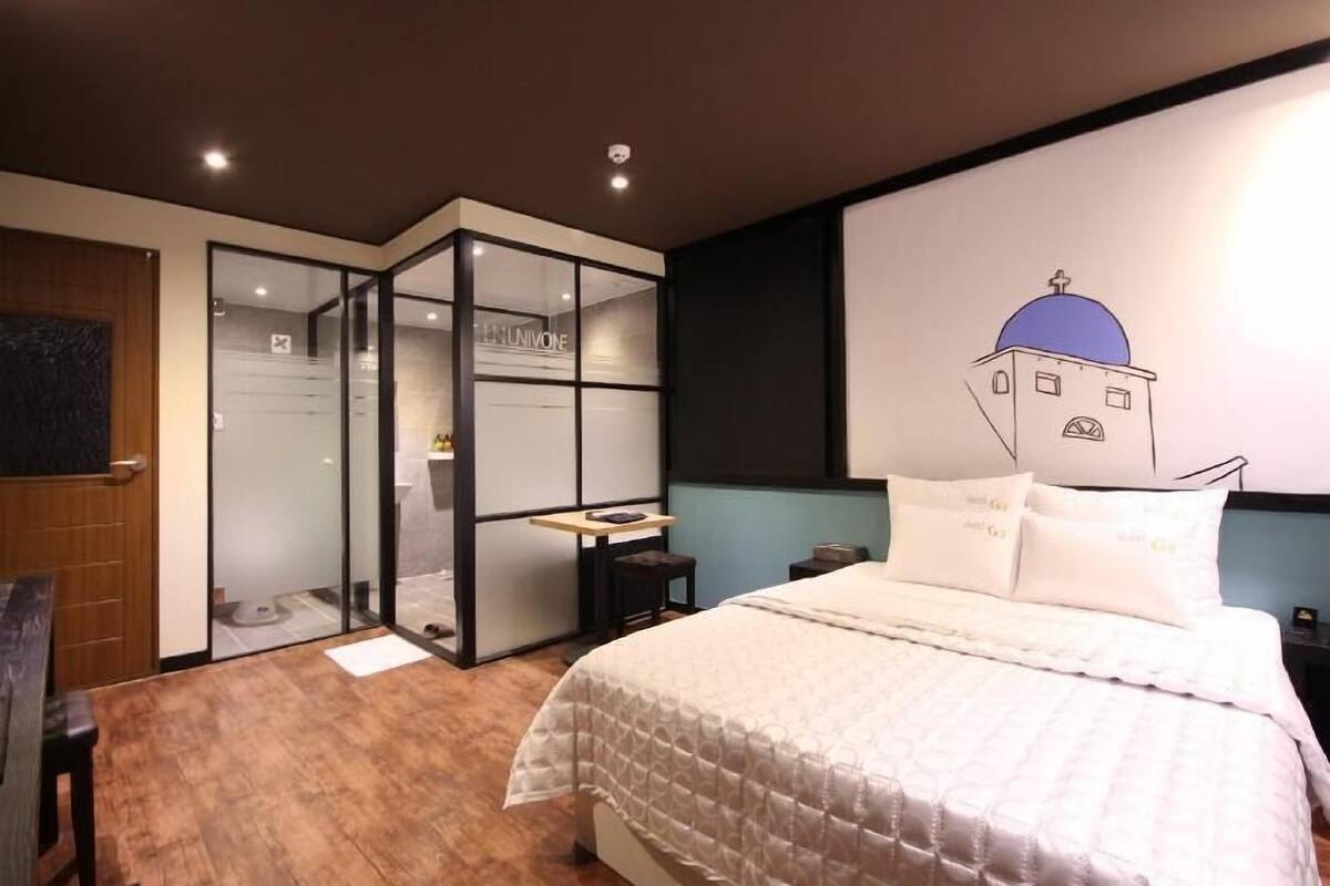 Ein modernes Hotelzimmer mit einem Bett, einem Schreibtisch und einer Glastrennwand.
