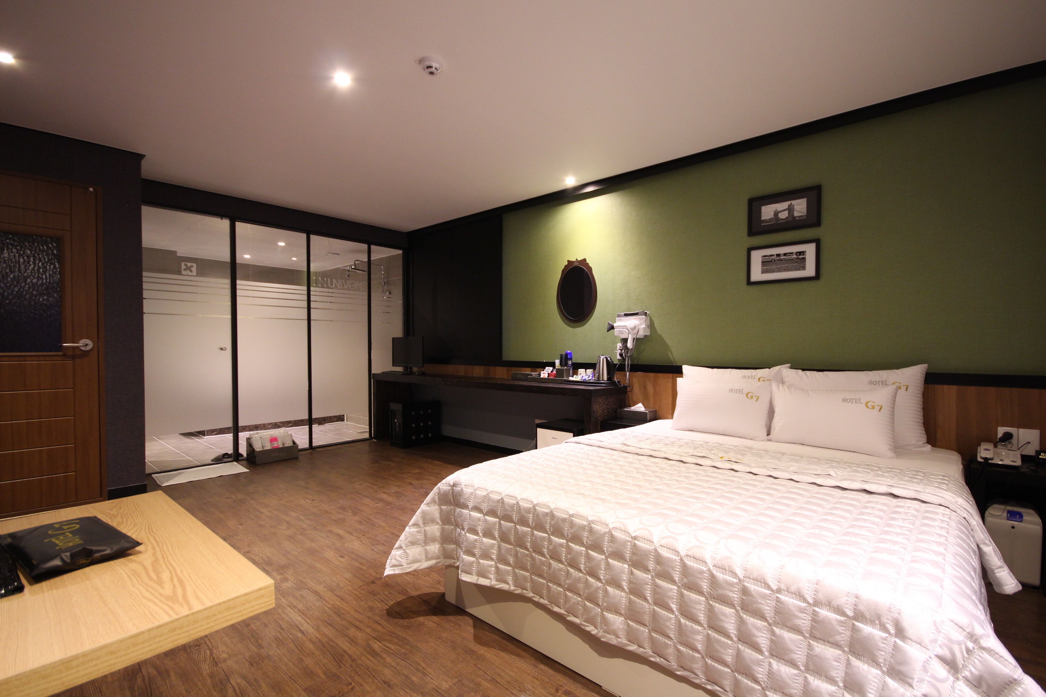 Una habitación de hotel con cama, escritorio, silla, armario y espejo.