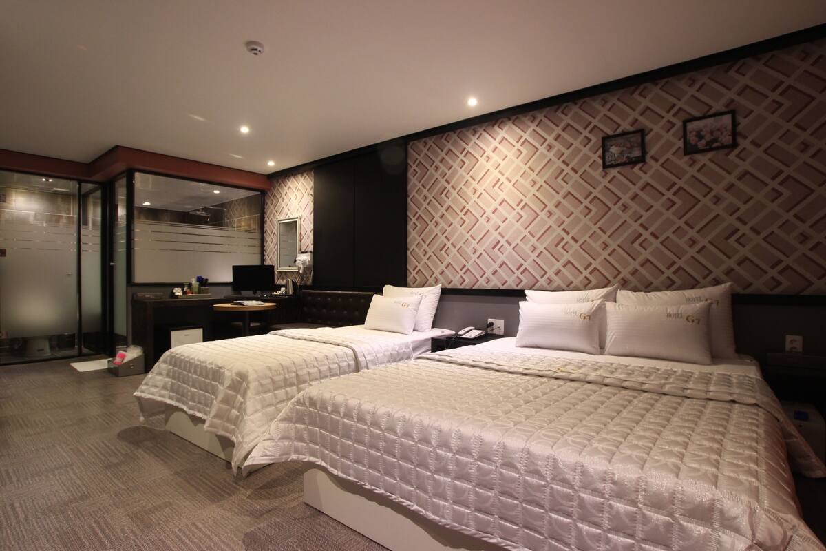 Ein Hotelzimmer mit zwei Betten, einem Schreibtisch, einem Spiegel und einer Wand mit Muster.
