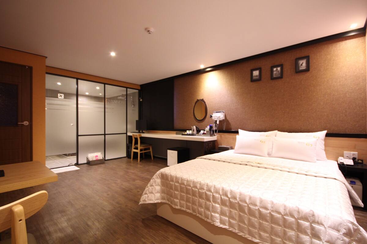 Ein Hotelzimmer mit Bett, Schreibtisch, Stuhl und einer Schiebetür zu einem Badezimmer.
