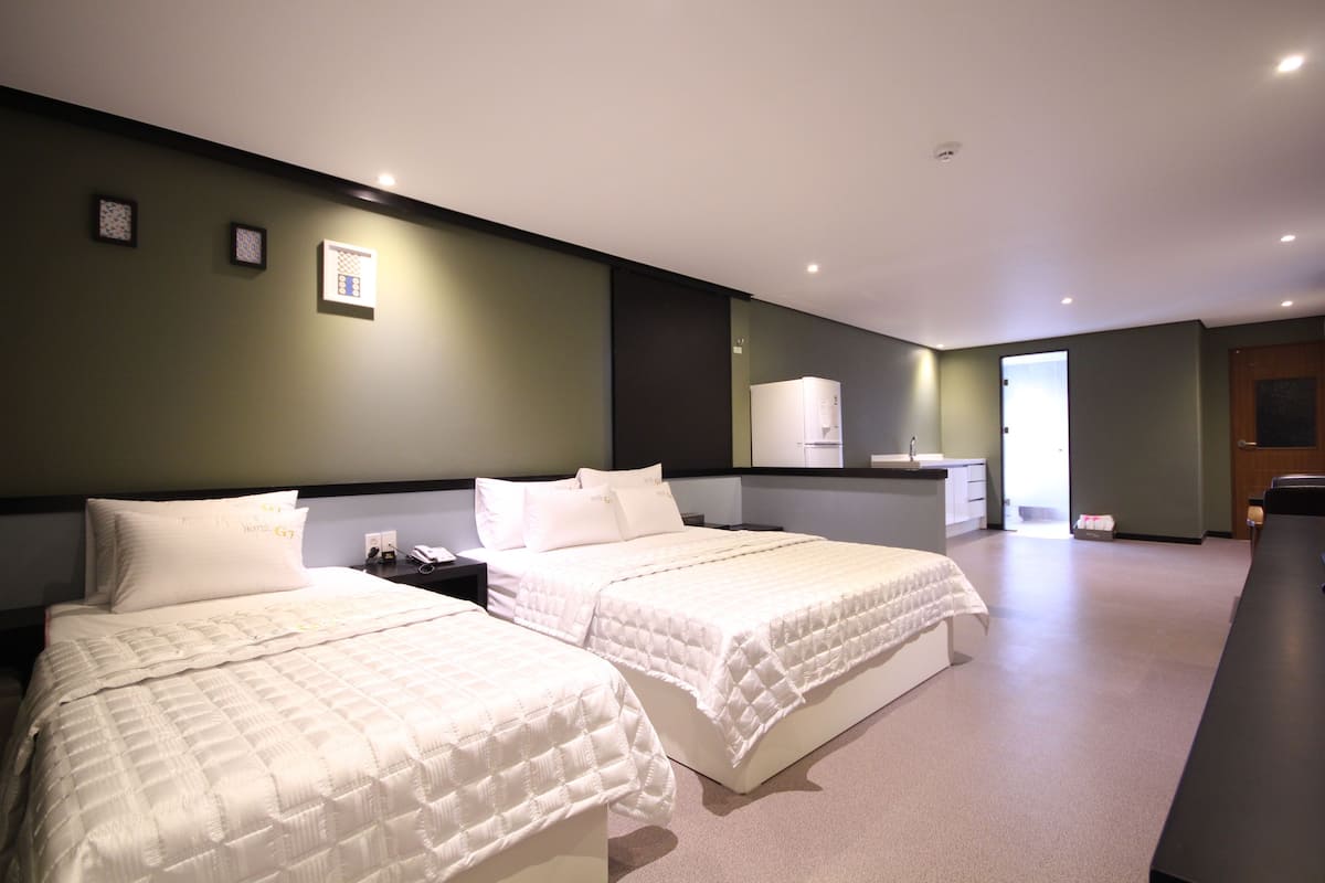 Ein Hotelzimmer mit zwei Betten, einem Schreibtisch, einem Spiegel und einer Tür.