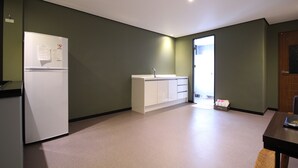 A small, clean kitchen with a refrigerator, sink, and cabinets. - G7 Hotel (Busan)