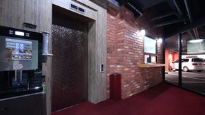 A modern elevator with a digital display, a red carpeted floor, and a brick wall. - G7 Hotel (Busan)