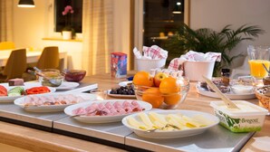 A breakfast buffet with various food items including meats, fruits, and dairy products. - Brink Hotell (Eslöv)