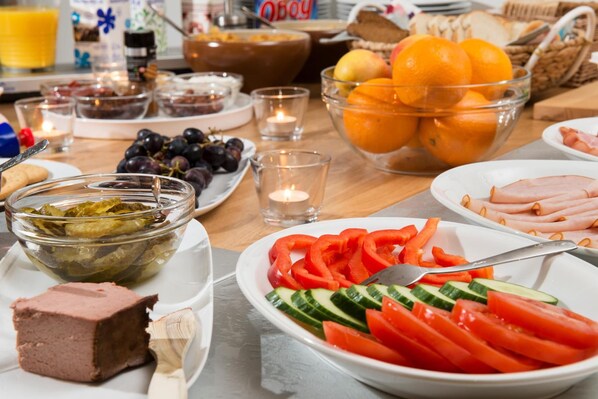 Una mesa de desayuno con diversos alimentos, como frutas, verduras y carnes.