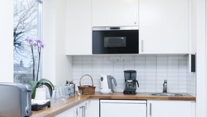 A modern kitchen with white cabinets, a built-in oven, a coffee maker, and a toaster. - Brink Hotell (Eslöv)