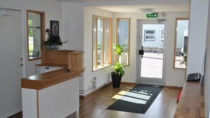 A reception area with a wooden counter, a potted plant, and a door leading outside. - Brink Hotell (Eslöv)