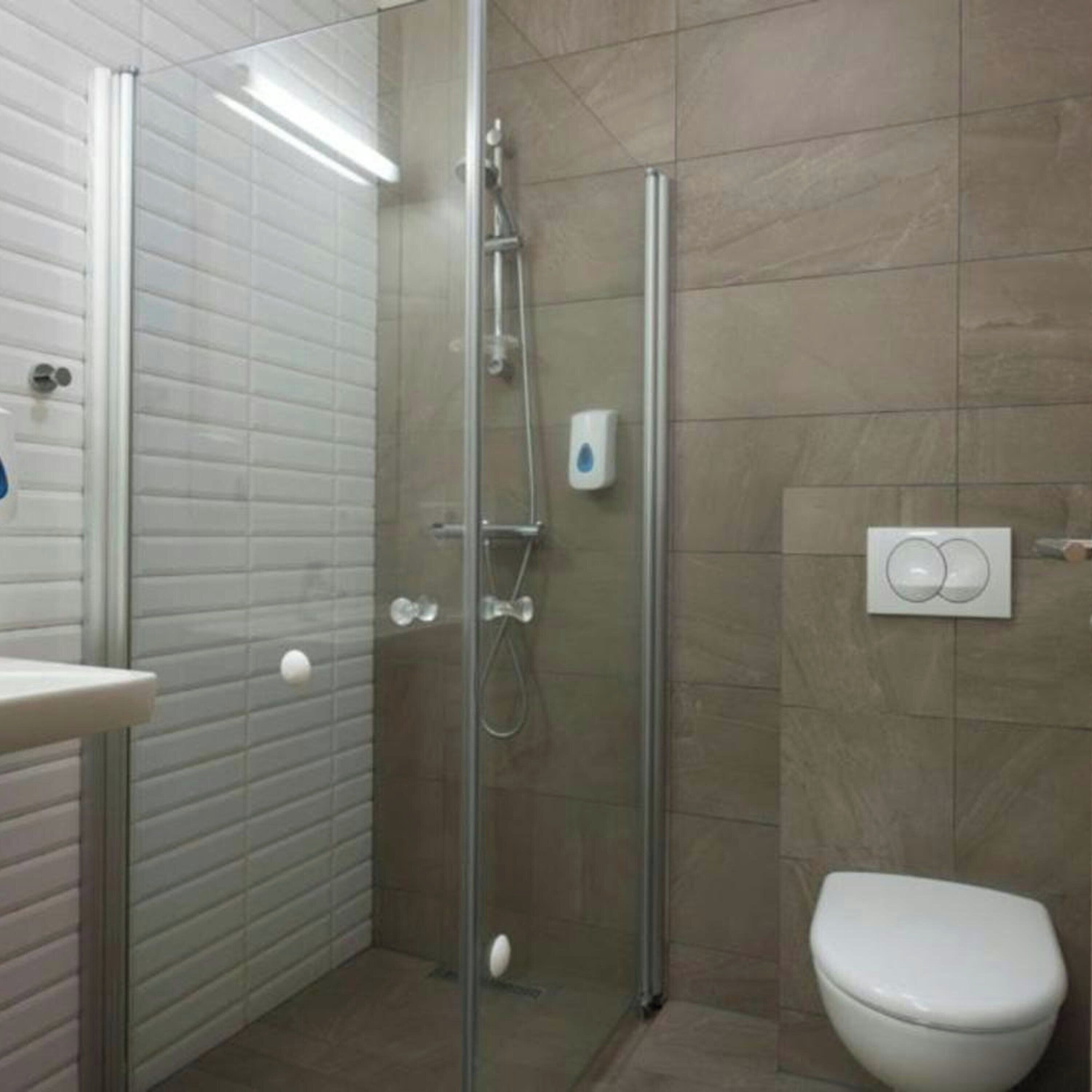 Une salle de bain avec une douche à parois de verre, des toilettes blanches et un lavabo avec un miroir.
