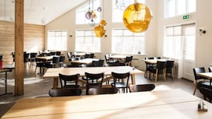 A spacious dining area with multiple tables and chairs, large windows, and hanging pendant lights. - Hotel Gullfoss (Bláskógabyggd)