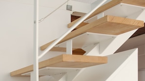 Una escalera moderna con escalones de madera y barandillas blancas.