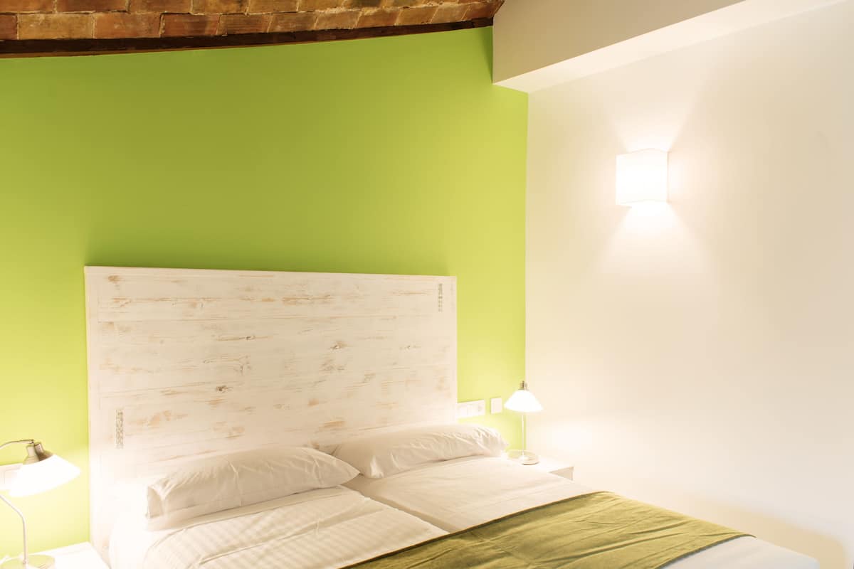 A room with a bed, green walls, and a white headboard.