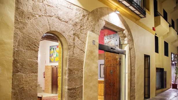 Un pasillo con arcos de piedra, una puerta de madera y un cartel arriba.