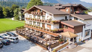 A hotel with a terrace, outdoor seating, and a view of the mountains. - Hotel Sonnhof (Radfeld)