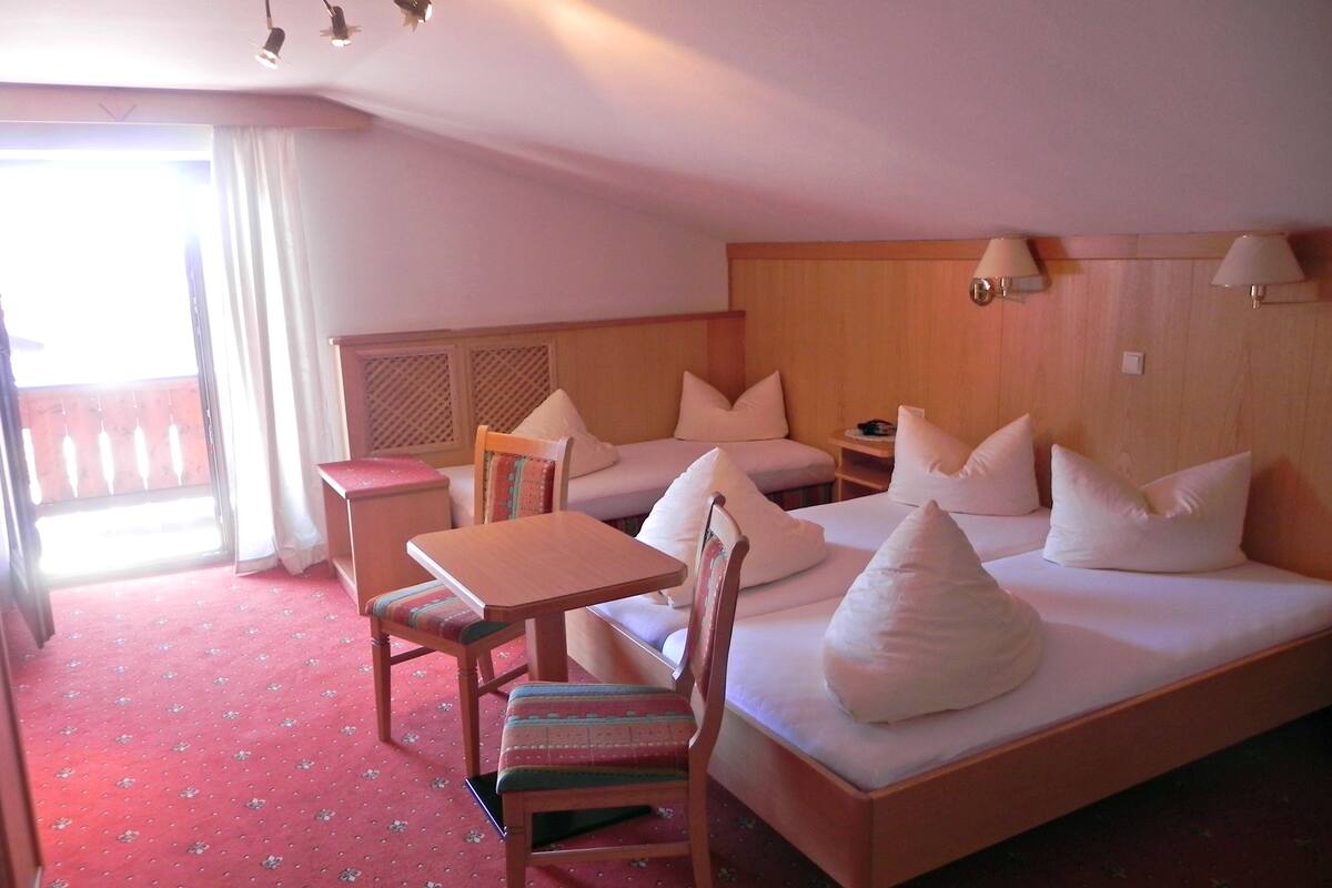 Habitació d'hotel amb llit, dues cadires, una taula petita i una cambrera de nit.