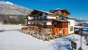 A multi-story hotel with a ski lift in the background, surrounded by snow-covered mountains. - Hotel Sonnhof (Radfeld)
