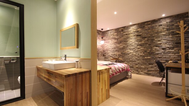A modern bathroom with a wooden vanity, a large mirror, and a separate shower area. - 25 Hours Hotel (Busan)