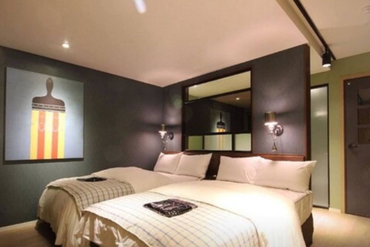 Habitación de hotel con dos camas, un espejo grande y un cuadro en la pared.