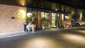 A hotel entrance with a brick facade, large windows, and potted plants. - 25 Hours Hotel (Busan)