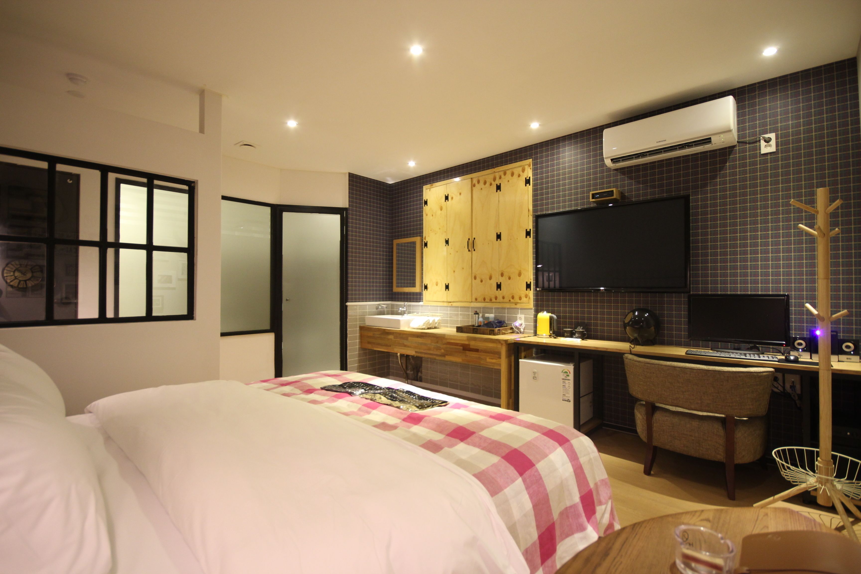 A modern hotel room with a large bed, a desk, a chair, and a TV.