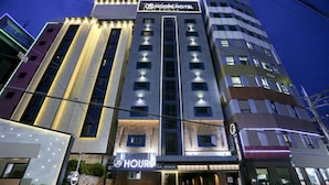 A multi-story hotel with a prominent sign for 'Hotel' and 'Hours' visible at the entrance. - 25 Hours Hotel (Busan)