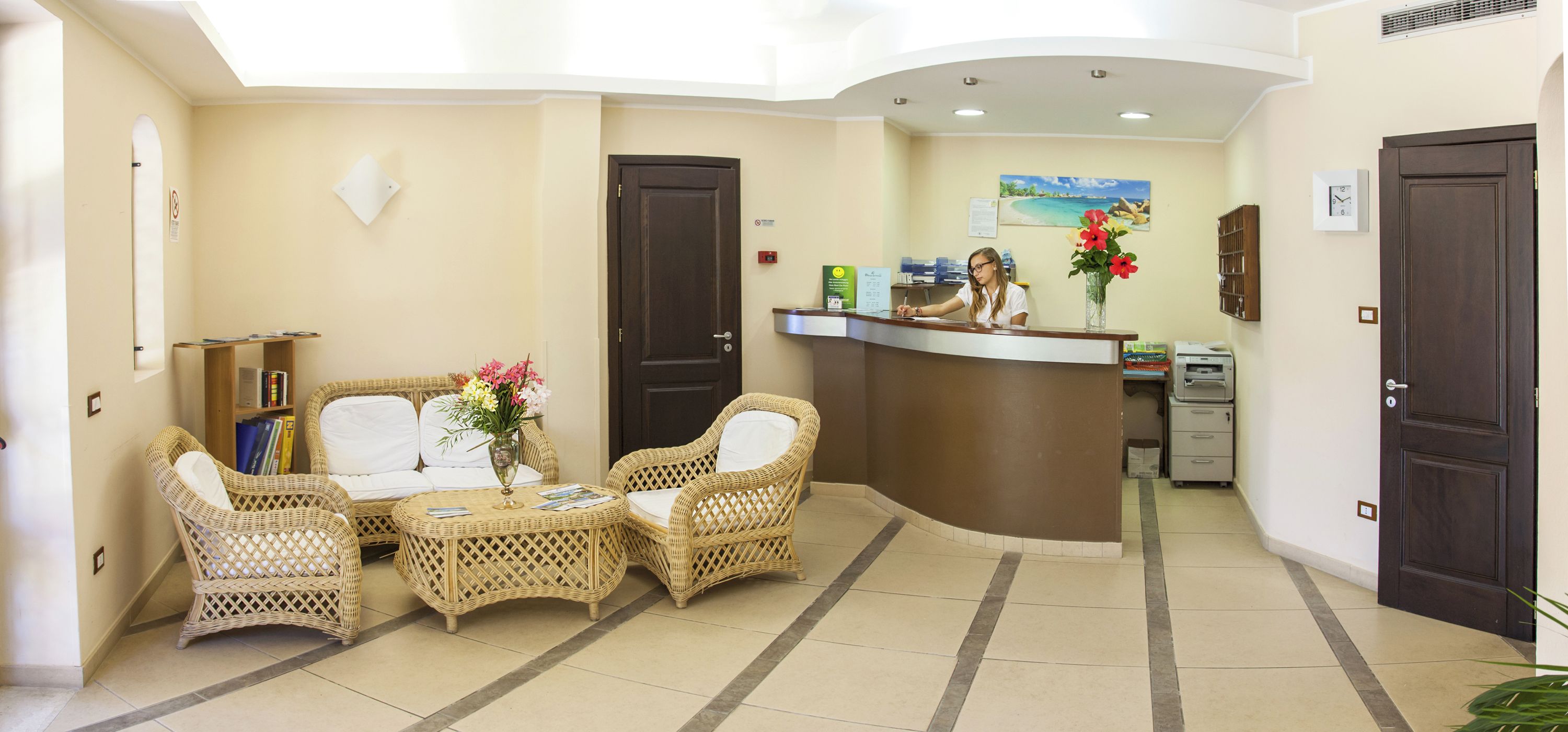 A reception area with wicker furniture, a reception desk, and a painting on the wall.