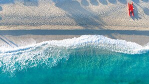 An aerial view of a beach with clear turquoise water, a sandy shore, and a red lifeguard stand. - Borgo del Principe by Valentour (Zambrone)