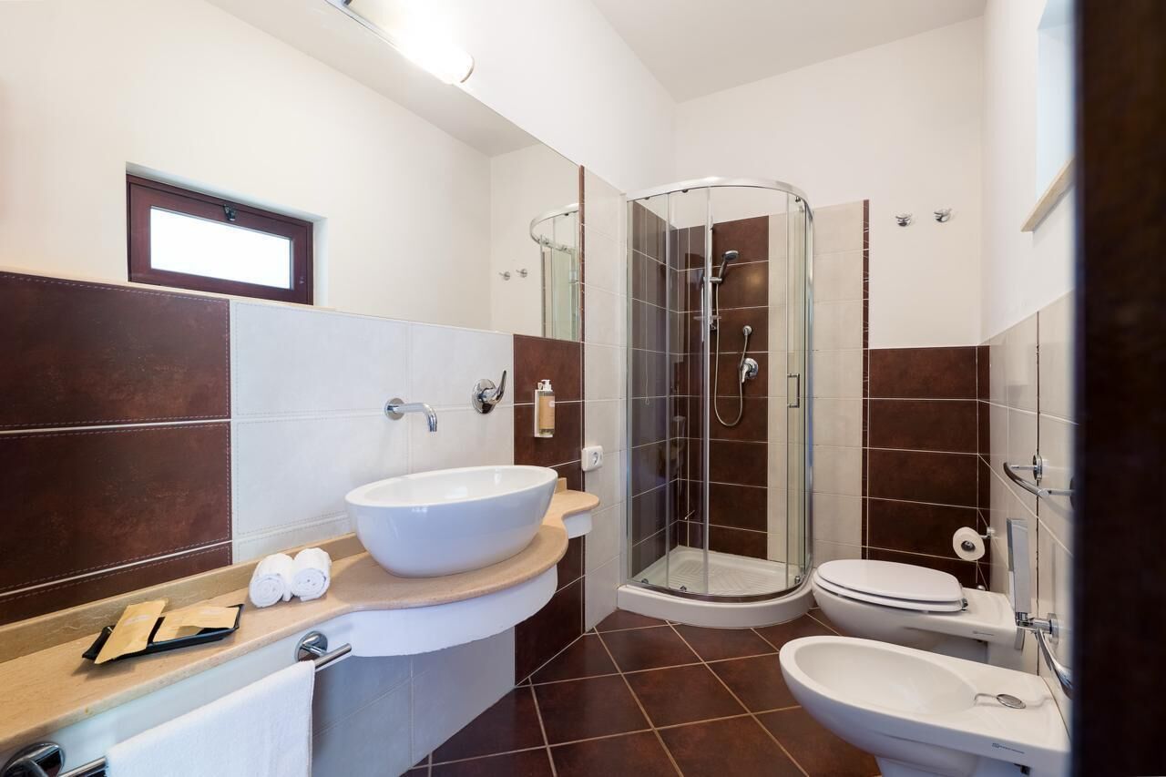 A modern bathroom with a glass-enclosed shower, a large white sink, and a separate bidet.