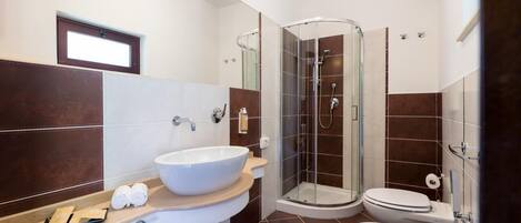 A modern bathroom with a glass-enclosed shower, a large white sink, and a separate bidet.