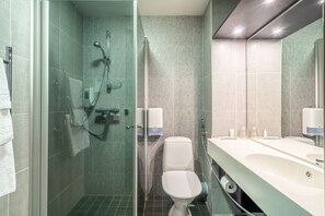 A modern bathroom with a glass-enclosed shower, a toilet, and a large vanity with a mirror.