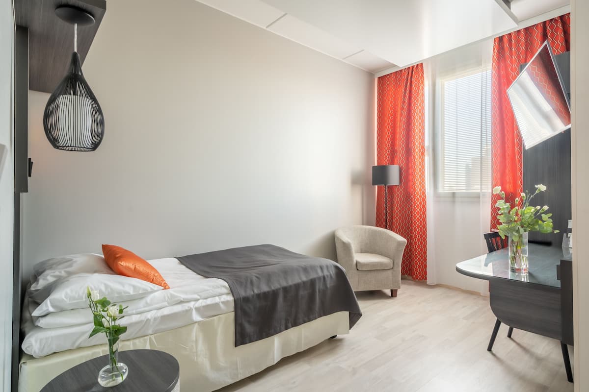 Une chambre d’hôtel moderne équipée d’un lit, d’une chaise, d’une petite table et d’un bureau.