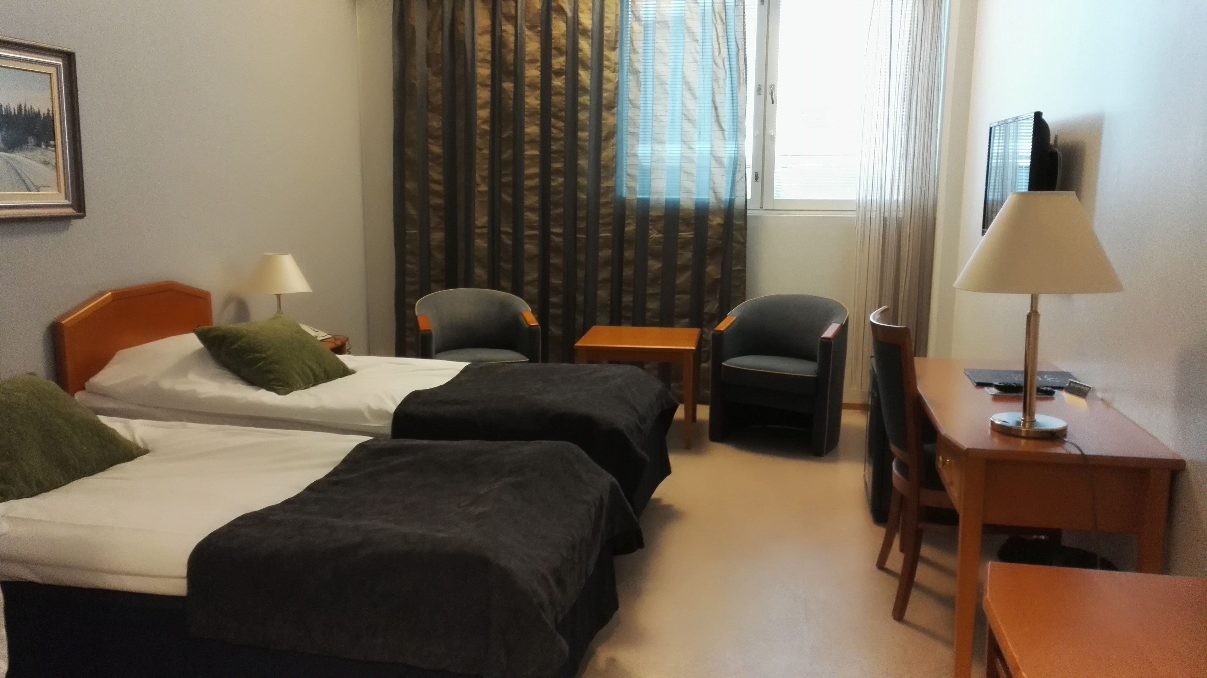 Una habitación de hotel con dos camas, un escritorio, una silla y una lámpara.