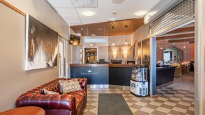 A reception area with a checkered floor, a leather sofa, a reception desk, and a coffee machine. - Hotel Raahen Hovi (Raahe)