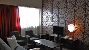 A modern living room with a sofa, armchairs, a coffee table, a TV, and a lamp. - Hotel Raahen Hovi (Raahe)