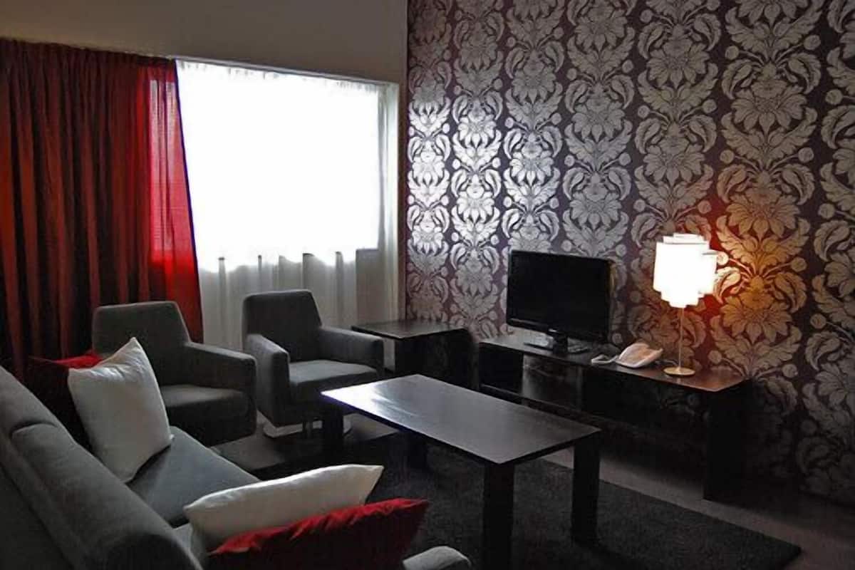 Un salon moderne comprenant un canapé, des fauteuils, une table basse, un téléviseur et une lampe.