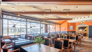 A spacious restaurant with high ceilings, large windows, and a variety of seating arrangements including tables and booths. - Hotel Raahen Hovi (Raahe)