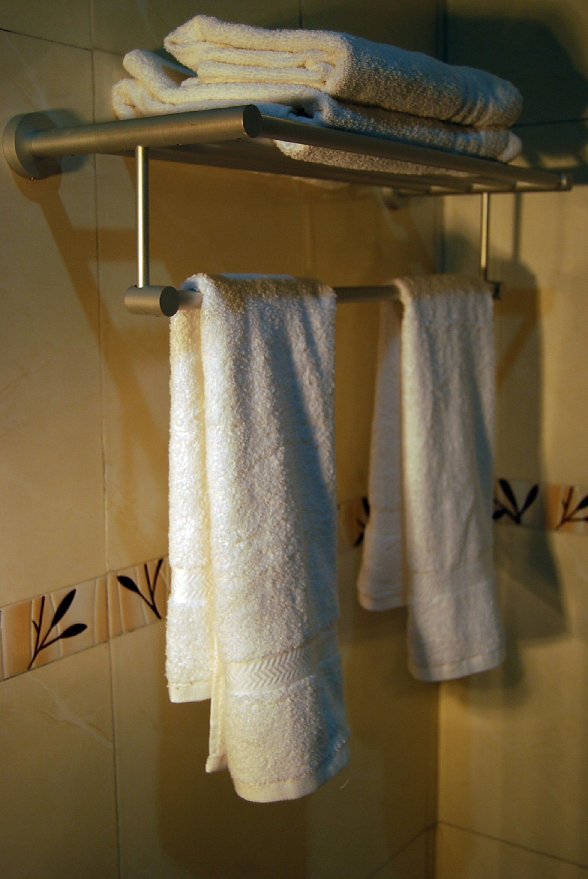 A bathroom with a towel rack holding several folded towels.
