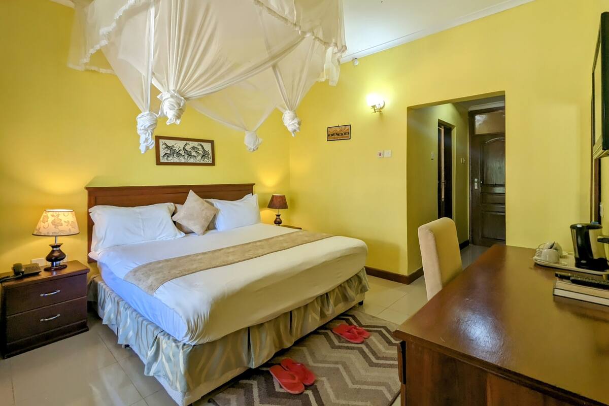 Una habitación de hotel con cama, lámparas de noche, una mesa y una silla.