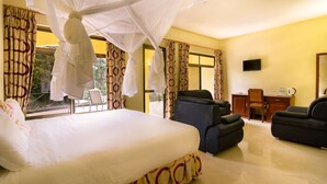 Une chambre d’hôtel avec un lit, un bureau, deux chaises et un téléviseur.