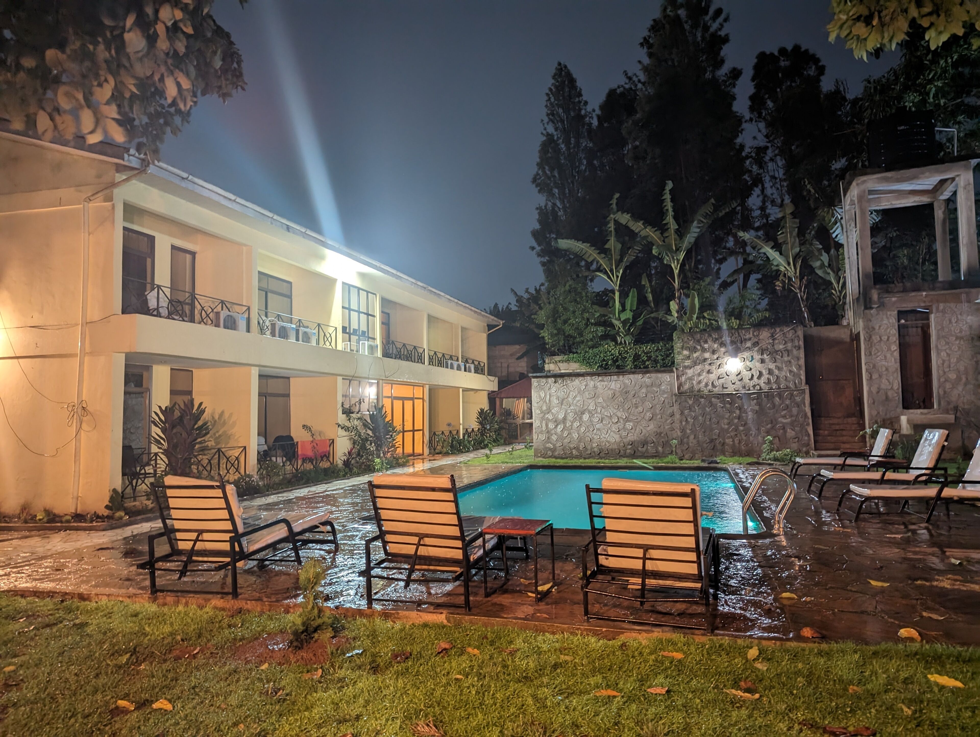 A hotel with a swimming pool, outdoor seating, and a well-lit building facade.