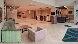 Een ruime lobby met een receptiebalie, een zithoek en een modern design.