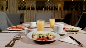 Een eettafel gedekt met borden eten, bestek en glazen sap.