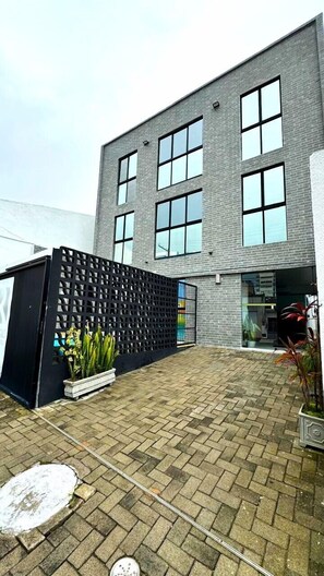 Welcome to a structured entrance with a black metal fence and potted plants, surrounded by a clean paved area.