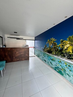 Welcome to our reception area, featuring a minimalist design with a large mural of a tropical scene and a comfortable chair.