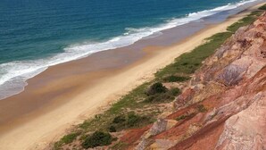 A coastal landscape with a sandy beach and rocky cliffs. - Hotel Refugio (Maceió)