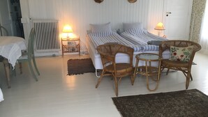 A room with a bed, two nightstands, a wicker chair, a small table, and a patterned rug. - Farm61 (Tjele)