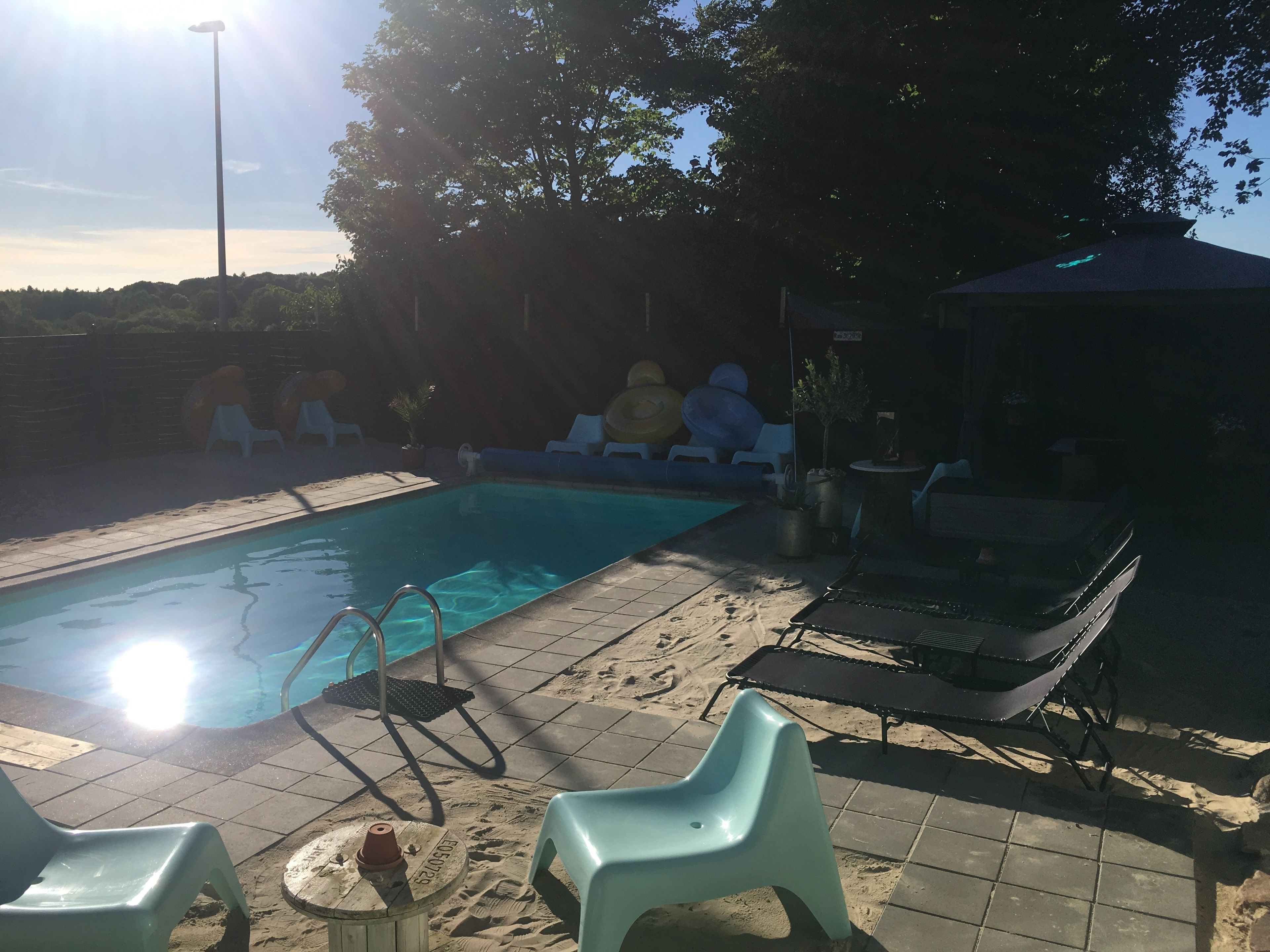 A swimming pool with lounge chairs and a covered area.