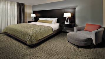 A hotel room with a bed, two bedside tables with lamps, a chair, and a carpeted floor.