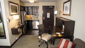 A compact hotel room with a kitchenette, a desk with a chair, a small sofa, and a bedside table. - Staybridge Suites Lexington by IHG (Lexington)