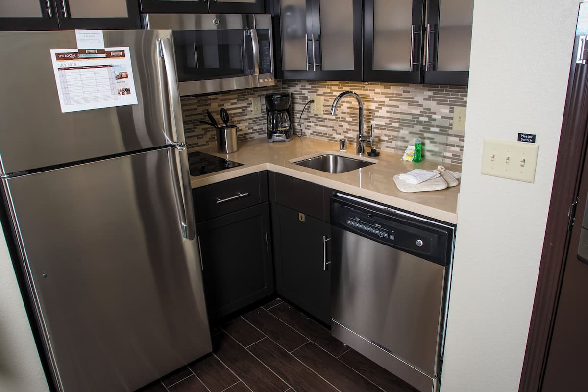 A compact kitchen with stainless steel appliances, a dishwasher, and a microwave.